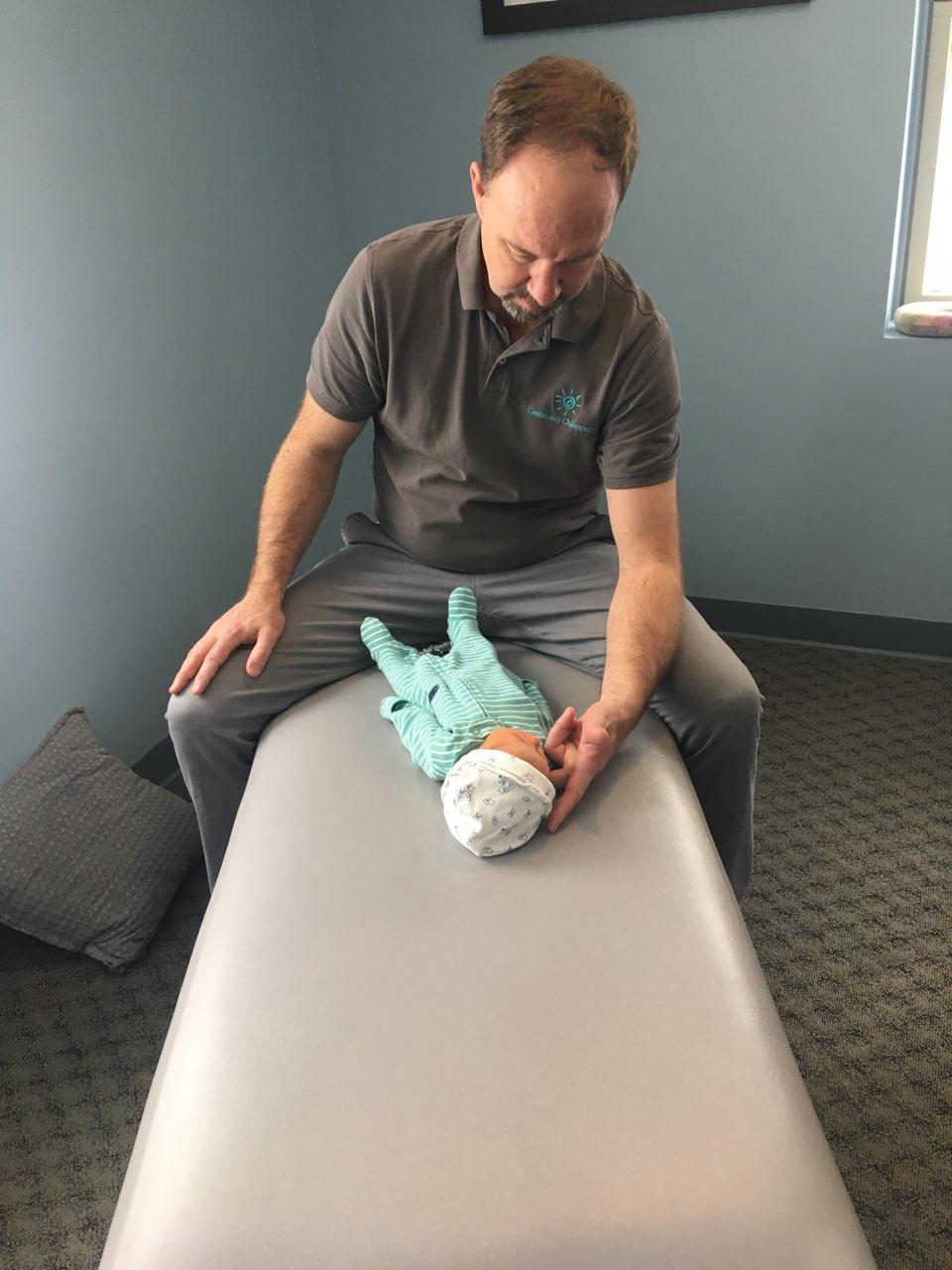 Dr. Steve Jarboe holding and adjusting a newborn baby