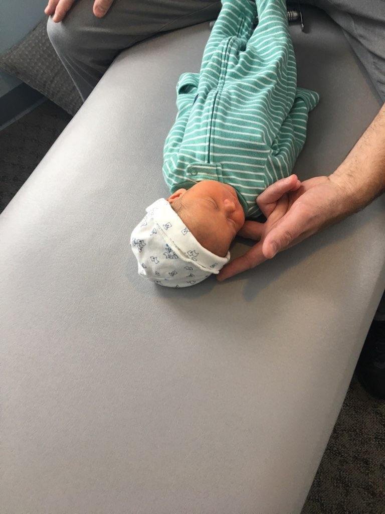 Close-up of a gentle chiropractic adjustment on a newborn