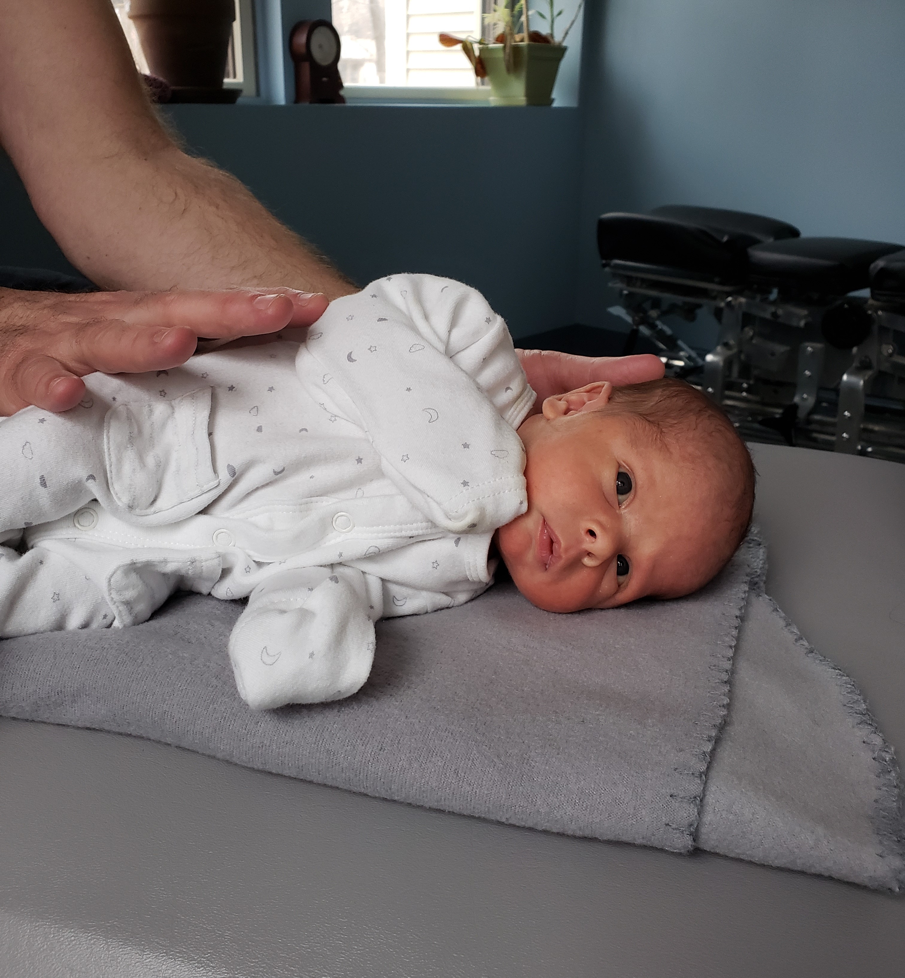 A 6-day-old baby receiving a gentle chiropractic adjustment